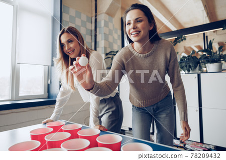 Young people coworkers playing beer pong in modern office Young people coworkers playing beer pong in modern office 78209432