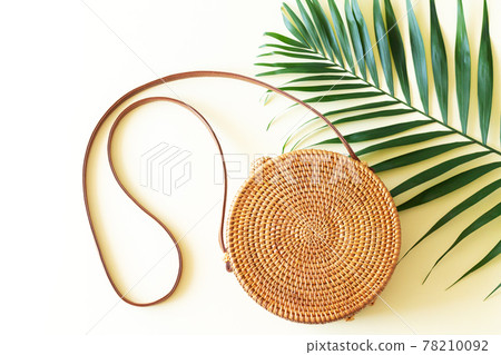 Rattan straw round bag and tropical palm leaf top view 78210092