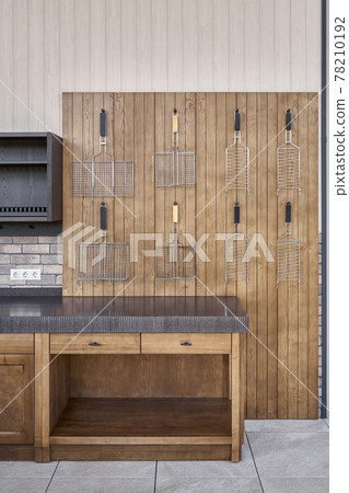 Barbecue grids hang on wainscoting in summer kitchen 78210192