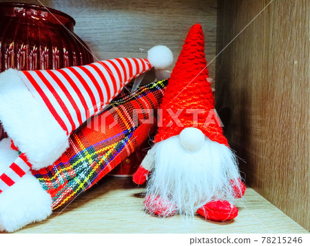 Plush toy gnome on the shelf next to the striped and checkered caps 78215246