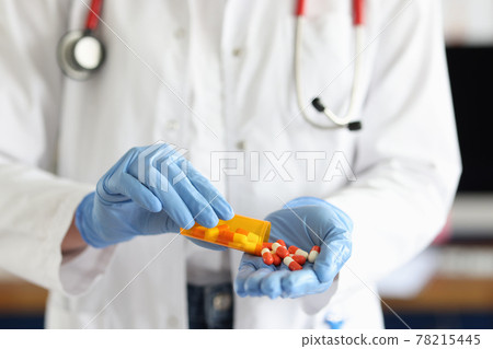 Doctor with medical gloves sprinkles pills on hand Doctor with medical gloves sprinkles pills on hand 78215445
