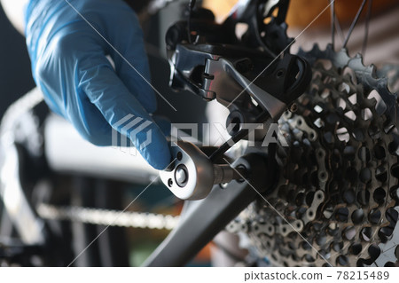Gloved handyman repairs rear cassette of sports bike Gloved handyman repairs rear cassette of sports bike 78215489