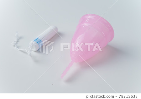 Pink menstrual cup and tampon on a white background. Various hygiene products during menstruation Pink menstrual cup and tampon on a white background. Various hygiene products during menstruation 78215635