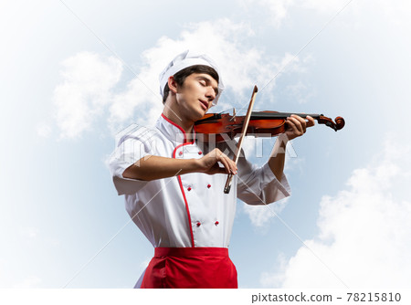 Young male chef playing violin 78215810
