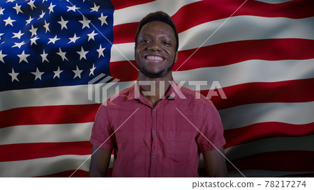 Black man smiling for camera against American flag Black man smiling for camera against American flag 78217274