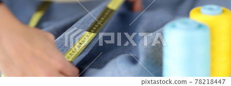 Seamstress measuring collar of dress with centimeter tape in sewing workshop Seamstress measuring collar of dress with centimeter tape in sewing workshop 78218447