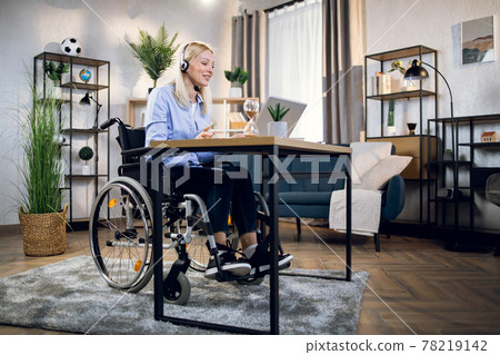 Handicapped woman using headset and laptop for video call Handicapped woman using headset and laptop for video call 78219142