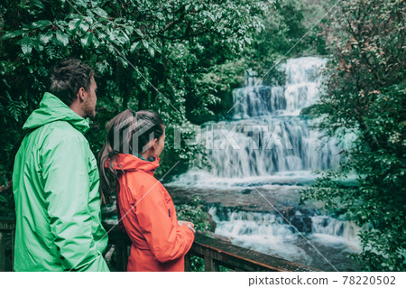 New Zealand tourists at waterfall nature landscape. People looking at Purakaunui Falls, a famous waterfall in the Purakaunui River in the Catlins of the southern South Island of New Zealand New Zealand tourists at waterfall nature landscape. People looking at Purakaunui Falls, a famous waterfall in the Purakaunui River in the Catlins of the southern South Island of New Zealand 78220502