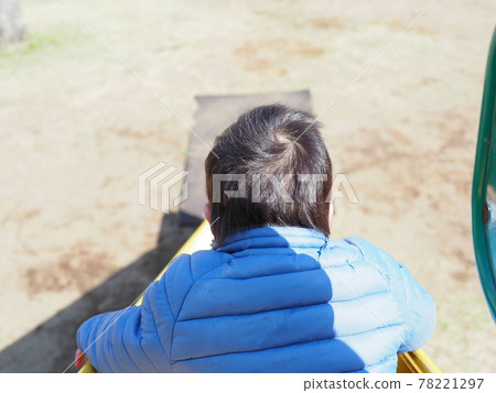 A boy trying to slide from a slide in the park, back view A boy trying to slide from a slide in the park, back view 78221297