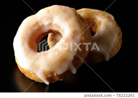 Two overlapping honey glaze donuts shot on a black background 78222261