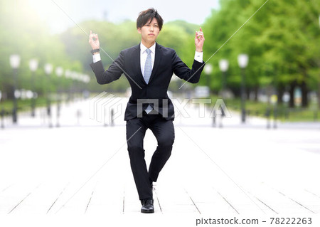 A young man in a suit dancing on the street 78222263