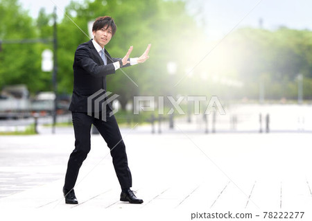 A young man in a suit dancing on the street 78222277