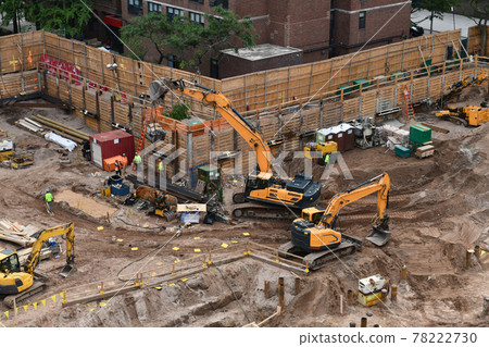 Excavators digging on skyscraper construction site with foundation pit 78222730