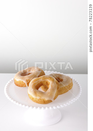 Photographed honey glaze donuts served on a cake stand on a white background Photographed honey glaze donuts served on a cake stand on a white background 78223139
