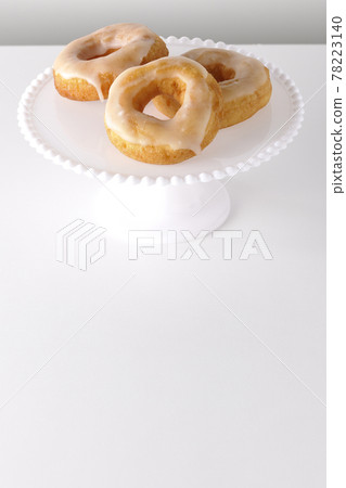 Photographed honey glaze donuts served on a cake stand on a white background Photographed honey glaze donuts served on a cake stand on a white background 78223140