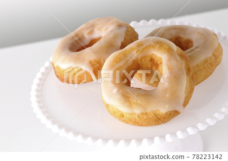 Photographed honey glaze donuts served on a cake stand on a white background Photographed honey glaze donuts served on a cake stand on a white background 78223142