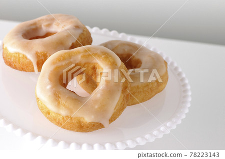 Photographed honey glaze donuts served on a cake stand on a white background Photographed honey glaze donuts served on a cake stand on a white background 78223143