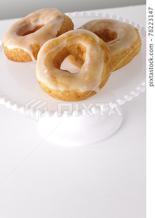 Photographed honey glaze donuts served on a cake stand on a white background Photographed honey glaze donuts served on a cake stand on a white background 78223147