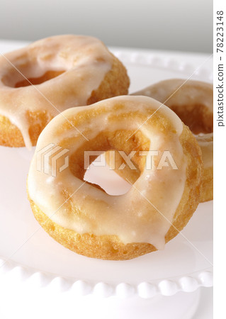 在白色背景的蛋糕架上供應拍攝的蜂蜜釉甜甜圈 在白色背景的蛋糕架上供應拍攝的蜂蜜釉甜甜圈 78223148