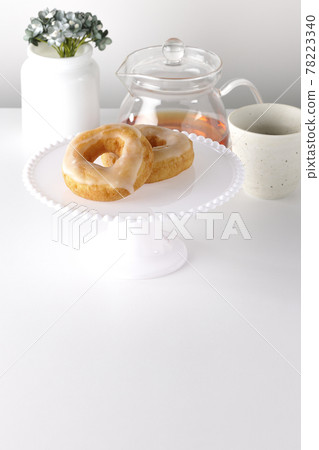 下午茶。蜂蜜釉甜甜圈和茶壺放在蛋糕架上 78223340
