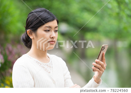 A woman who feels uncomfortable looking at her smartphone and is white 78224560