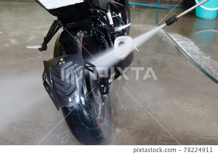 Wash the motorbike at the car wash shop. 78224911