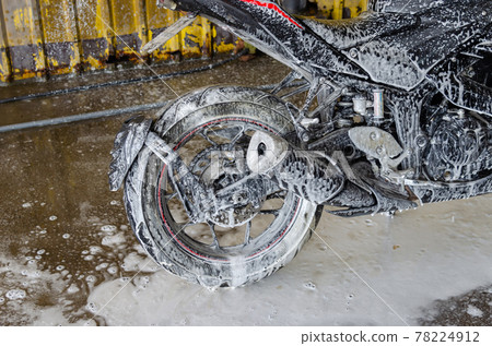 Wash the motorbike at the car wash shop. 78224912