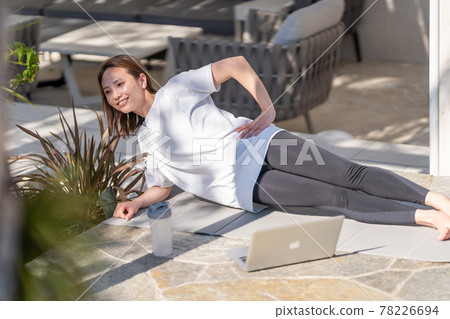 Young woman doing online muscle training at home 78226694