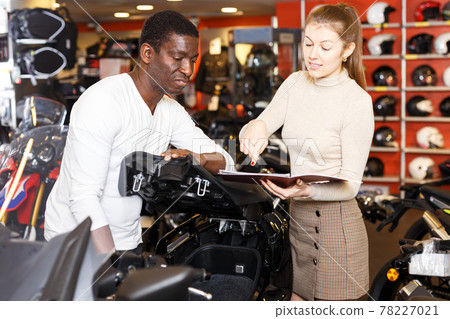 Salesgirl and customer in motorcycle shop Salesgirl and customer in motorcycle shop 78227021