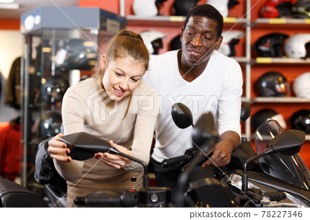 Portrait of active man and woman looking new motorbike at motosalon showroom Portrait of active man and woman looking new motorbike at motosalon showroom 78227346