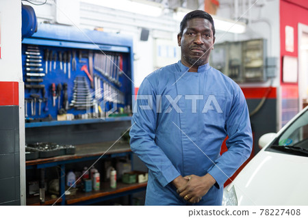 Professional man car mechanician standing near repairable car in auto service Professional man car mechanician standing near repairable car in auto service 78227408