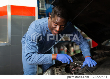 Professional american mechanic man in uniform repairing car engine Professional american mechanic man in uniform repairing car engine 78227551