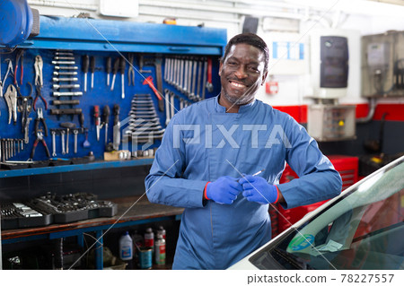 Portrait of confident mechanician posing near car at service Portrait of confident mechanician posing near car at service 78227557