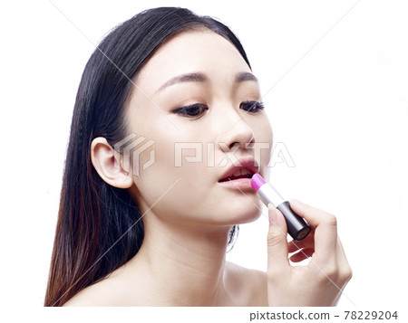 young and beautiful asian woman applying pink lipstick, isolated on white background young and beautiful asian woman applying pink lipstick, isolated on white background 78229204