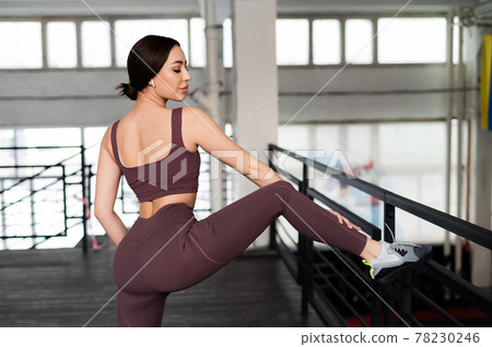 Beautiful young athletic woman posing after an active workout in the gym. European girl listens to music on wireless headphones during fitness. 78230246