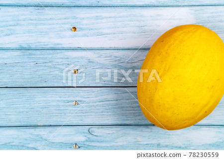 A whole yellow melon lies on a blue wooden background.Summer concept A whole yellow melon lies on a blue wooden background.Summer concept 78230559