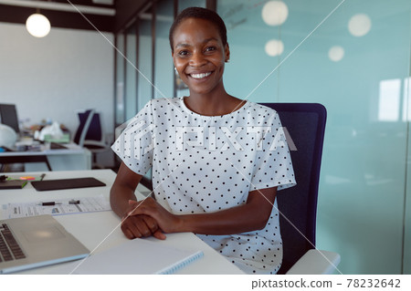 Smiling african american businesswoman sitting at desk at work 78232642