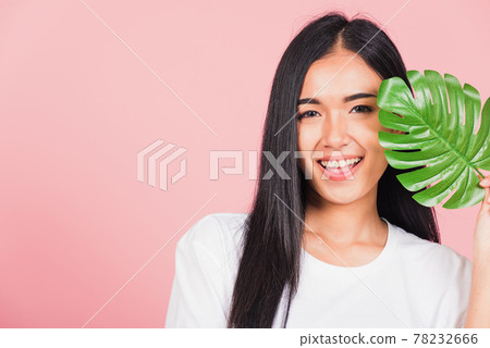 woman with fresh healthy skin hold green monstera leaf on her face woman with fresh healthy skin hold green monstera leaf on her face 78232666
