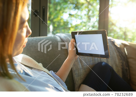 Asian woman using tablet with blank screen, sitting on sofa at home Asian woman using tablet with blank screen, sitting on sofa at home 78232689