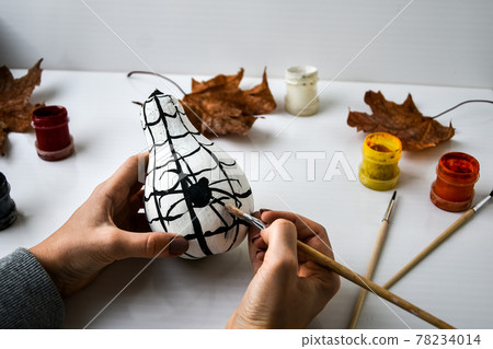 Woman paints spider on pumpkin for Halloween. Autumn leaves. Diy children craft. Do it yourself. Woman paints spider on pumpkin for Halloween. Autumn leaves. Diy children craft. Do it yourself. 78234014