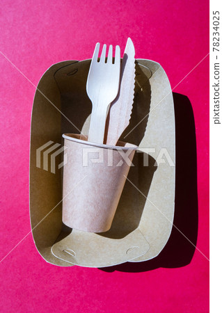 Wooden forks and paper cups with plates on color background. Eco friendly disposable tableware. Used in fast food, restaurants, takeaways, picnics. No plastic 78234025