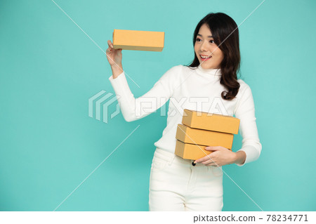 Happy Asian woman smiling and holding package parcel box isolated on light green background, Delivery courier and shipping service concept Happy Asian woman smiling and holding package parcel box isolated on light green background, Delivery courier and shipping service concept 78234771