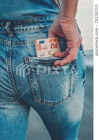 A woman's hand takes out euro bills from the back pocket of her jeans. The concept of finance, savings, financial expenses. Close-up 78236313