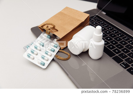 Online pharmacy concept. Pills and spray containers and buff paper bags on the keyboard Online pharmacy concept. Pills and spray containers and buff paper bags on the keyboard 78236899