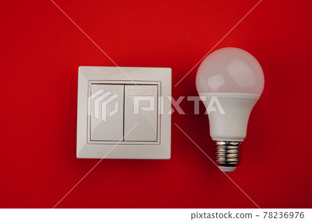 Light bulb and white switch on red background Light bulb and white switch on red background 78236976