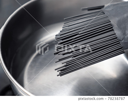 Uncooked black spaghetti above saucepan Uncooked black spaghetti above saucepan 78238787