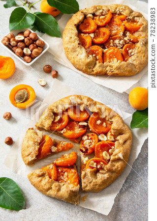 Healthy pastries made from rye flour, dessert diet food. Galette with apricots and nuts on a light stone table. 78238983