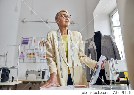 Middle aged woman at table with sewing machine in light workshop low angle view 78239166
