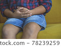 Asian child suffering from stomachache location of pain. The boy is sitting on the couch suffering from nausea next to windows in living room, parental care, stomach problems, healthy concept. 78239259