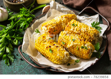 Summer vegan dinner or snacks. Grilled corn with garlic butter, served with cheese on a dark stone table top. Summer vegan dinner or snacks. Grilled corn with garlic butter, served with cheese on a dark stone table top. 78239858